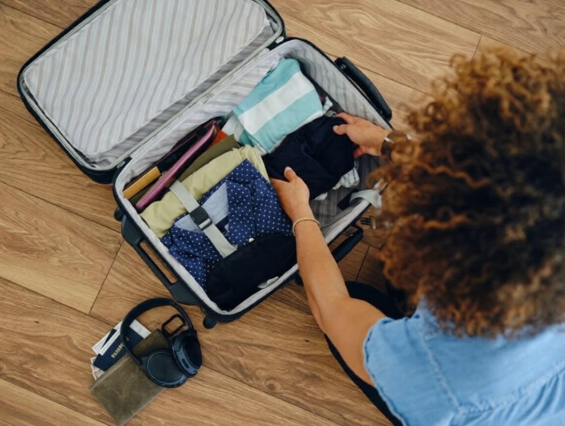 Person packing a suitcase on a wooden floor