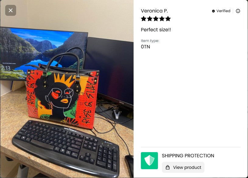 Colorful handbag with artistic design on a desk next to a computer setup